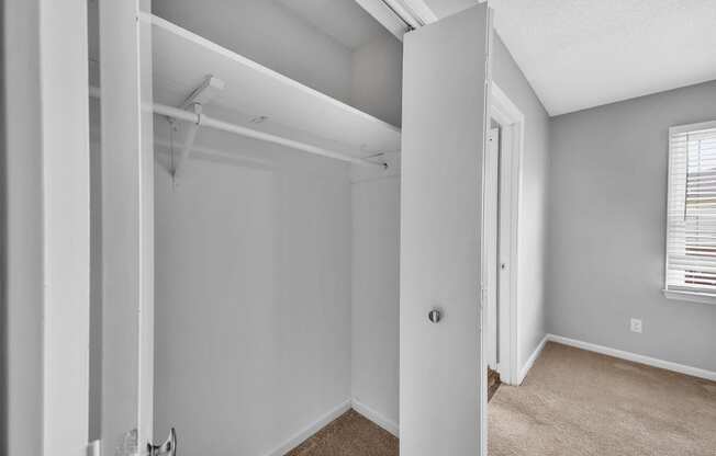 the living room of an apartment with white walls and a door to a closet