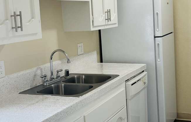 Kitchen with white cabinets and appliances at Plaza Verde Apartments in Escondido, California.