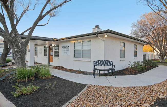 A small white building with a black and white checkered bench in front of it.