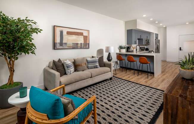 A living room with a grey couch, a blue chair, and a painting on the wall.