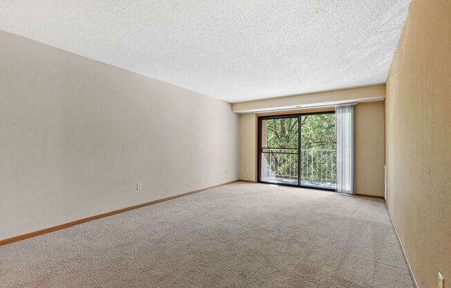 an empty living room with a sliding glass door to a balcony