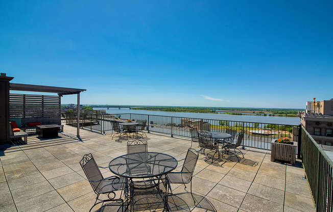 a large patio with tables and chairs overlooks a body of water