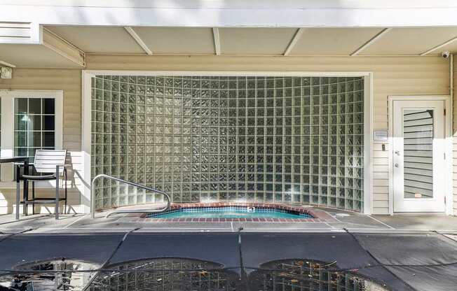 A jacuzzi with a glass block wall behind it.