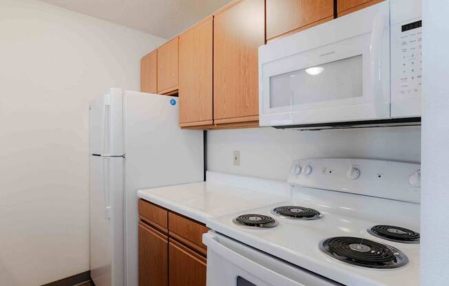 A white microwave oven is mounted above a white stove in a kitchen.