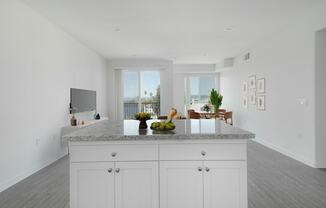 a white kitchen with a granite counter top and a living room