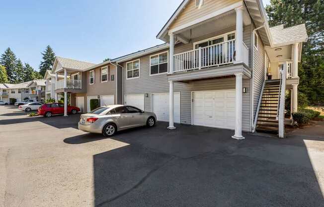 A silver car is parked in a driveway in front of a two-story house.