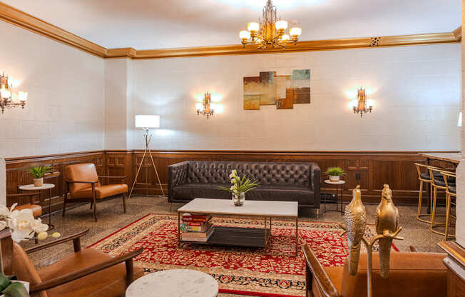 A living room with a black couch and a chandelier.