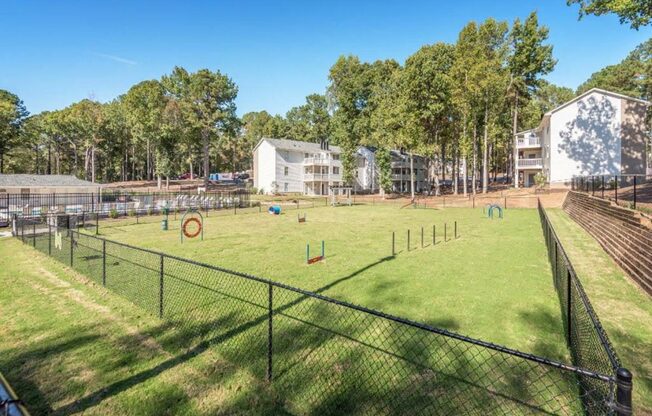 a fenced in dog park in front of a building