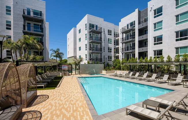 A large swimming pool surrounded by lounge chairs and palm trees.