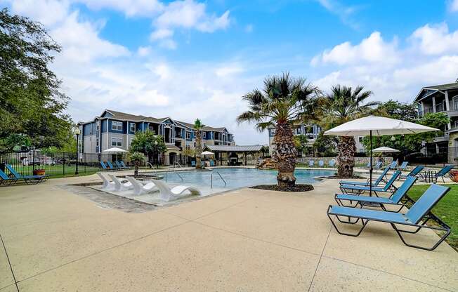 a large pool with lounge chairs and umbrellas at the enclave at woodbridge apartments in