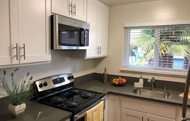 a kitchen with white cabinets and a microwave and a window