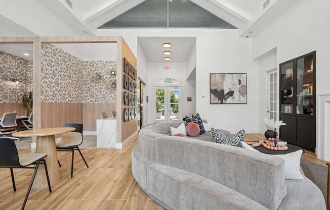 A modern living room with a grey sofa and a wooden dining table.