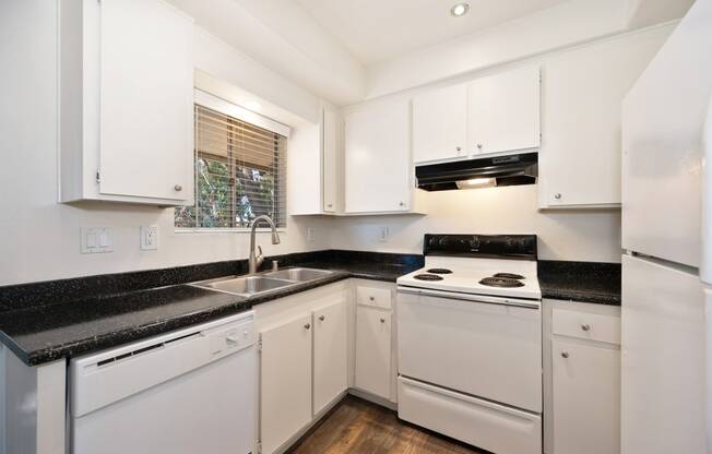 a kitchen with white appliances and black counter tops and white cabinets