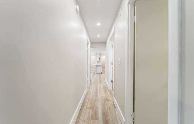 A long hallway with white walls and wood floors.