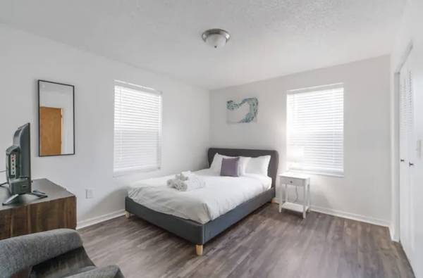 a white bedroom with a bed and a chair