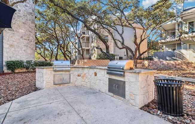 A stone wall with a fireplace and a trash can in front of it.
