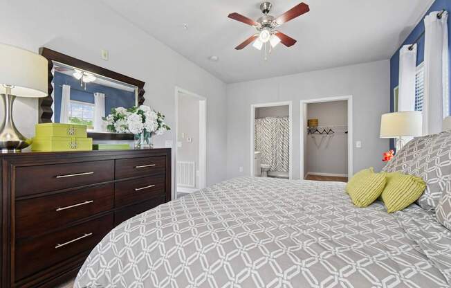 A bedroom with a patterned bedspread and a ceiling fan.