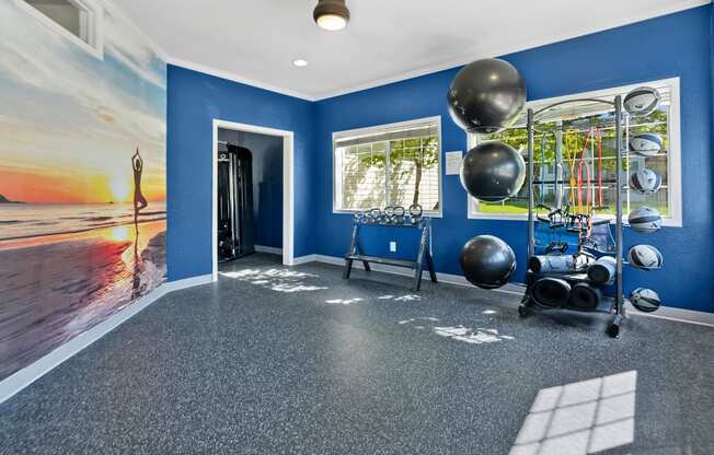 A room with a blue wall and a picture of a sunset on the wall.