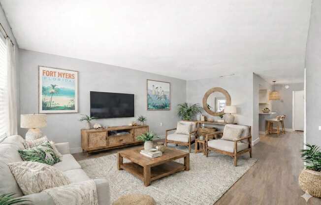 A living room with a flat screen TV, a white sofa, and a wooden coffee table.