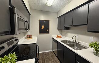 A kitchen with black cabinets and a white countertop.