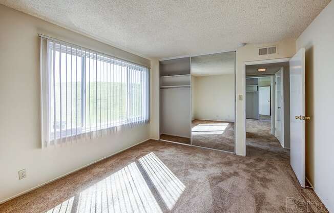 a bedroom with a large window and carpeted flooring at Terrace View Apartments, Daly City, 94015