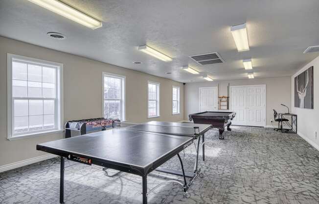 a recreation room with two ping pong tables and a foosball table