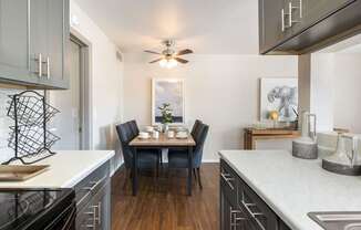 an open kitchen with a dining table and a ceiling fan