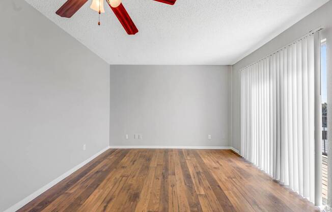 A room with a ceiling fan and wooden flooring.