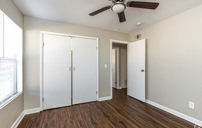 A room with a ceiling fan and a white door.