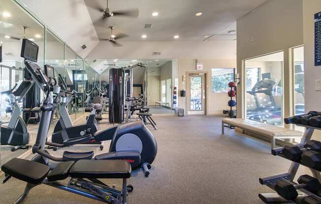 The 24-hour fitness center with treadmills, elliptical machines, and free weights at The Brownstones Townhome Apartments in the Far North Dallas neighborhood of Dallas, TX..