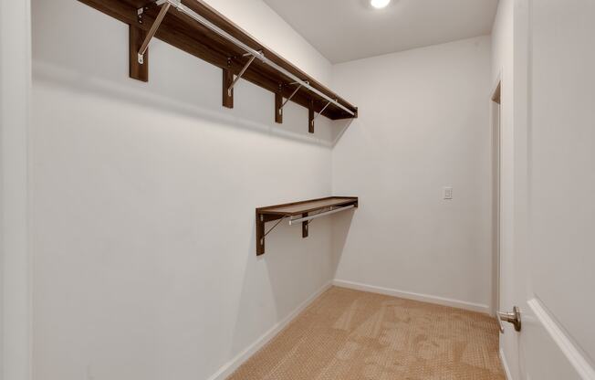 a room with a white wall with a closet and a hanging rail on the wall