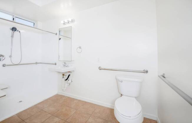 A white toilet in a bathroom with a white sink and a shower.