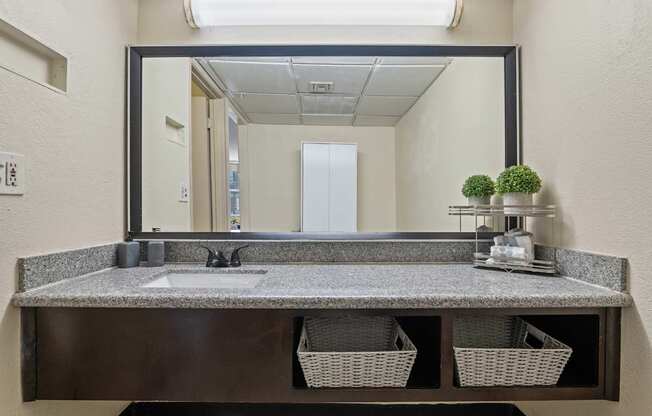 A bathroom vanity with a mirror, sink, and baskets.