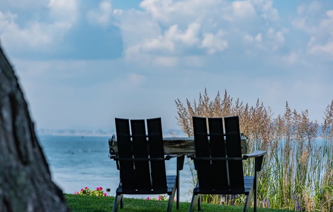 pair of black lawn chairs sit in front of a wa pair of black lawn chairs sit in front of a wooden table with a view of the