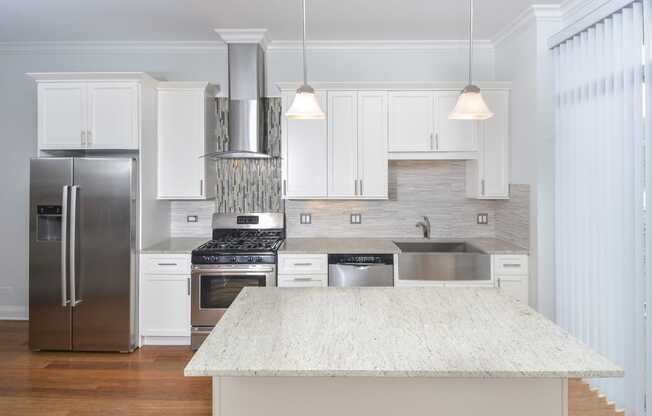 a large white kitchen with stainless steel appliances and a white island