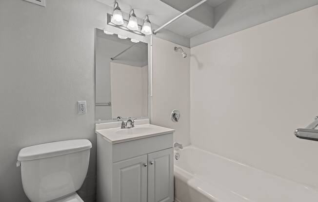 A white bathroom with a toilet, sink, and bathtub.