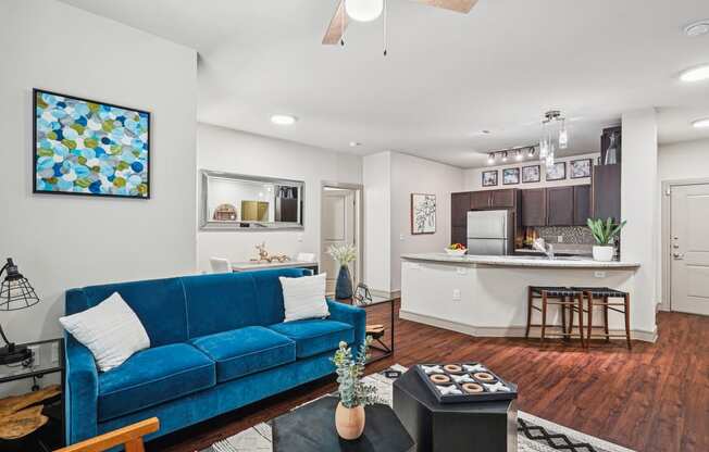 a living room with a blue couch in front of a kitchen