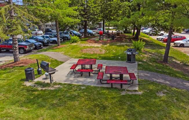 two picnic tables and benches in a park next to a parking lot
