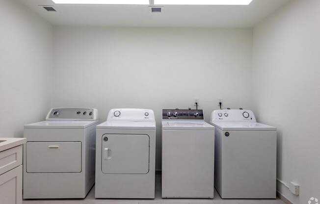 a row of washers and dryers in a laundry room with white appliances