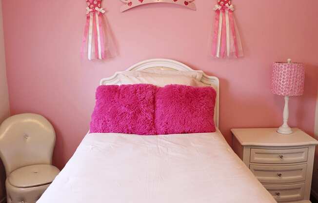 a pink princess bedroom with pink walls and a white bed