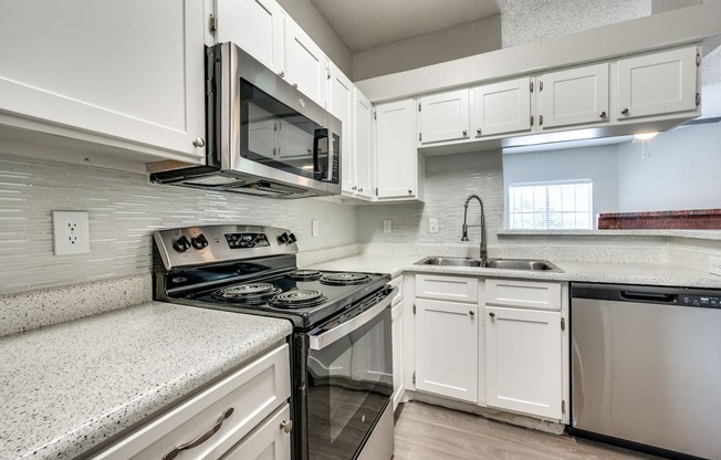an empty kitchen with white cabinets and a stove and microwave at Foxborough Apartments, Irving, TX, Texas, 75061