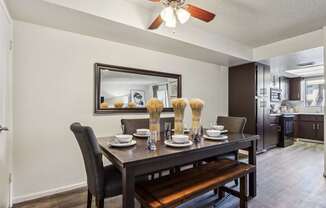A dining room with a table set for two and a bench.