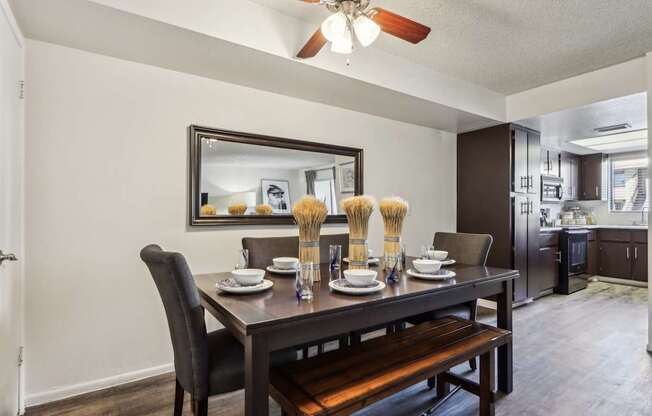 A dining room with a table set for two and a bench.