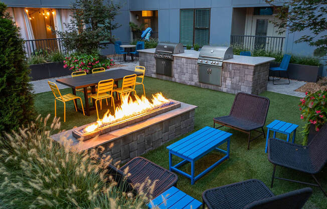 a fire pit in the middle of a yard with chairs and tables