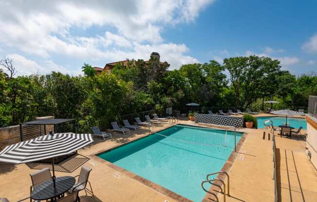 a resort style pool with lounge chairs and umbrellas