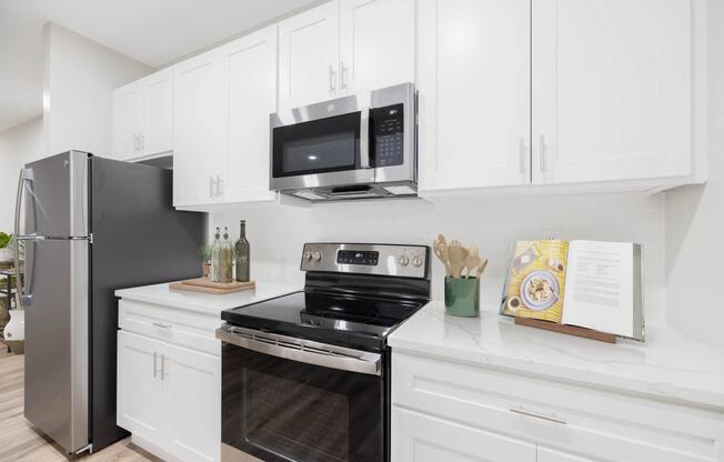 a white kitchen with stainless steel appliances and a microwave