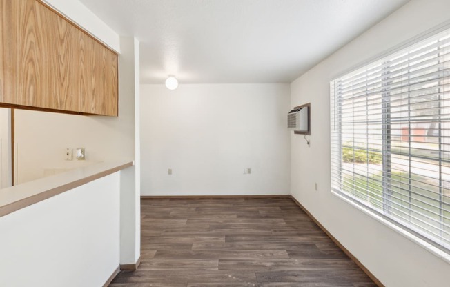 an empty living room with a large window and a kitchen