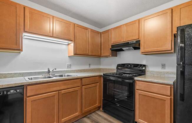 A kitchen with black appliances and wooden cabinets.