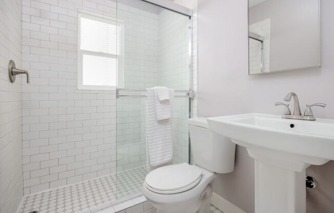 a bathroom with white tiles and a white sink and toilet