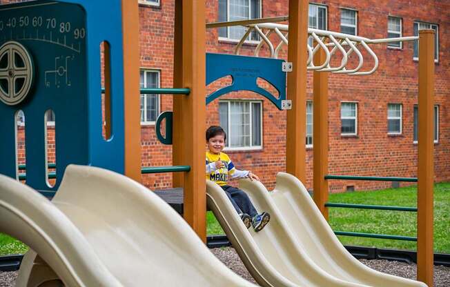 a boy is sitting on a slide on a playground at Hamilton Manor Apartments, Hyattsville, 20782